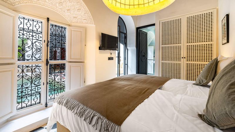 Bedroom 1: the beds under a brown throw, facing the wrought-iron windows onto the courtyard.