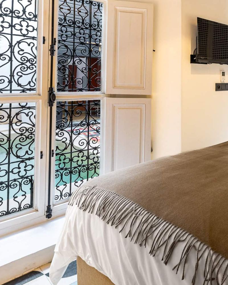 La chambre 1 : les lits sous un plaid brun, face aux fenêtres en fer forgé qui donnent sur le patio.