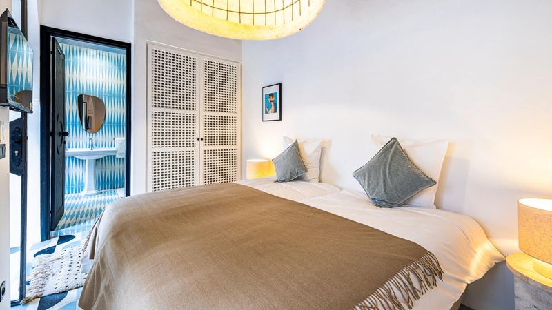 Bedroom 1: the beds under a brown throw, a wardrobe with pierced doors and an open black door.