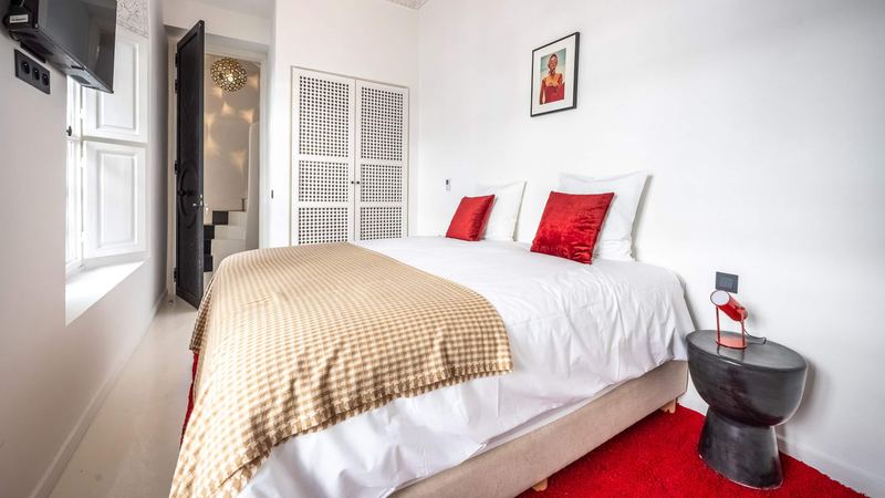 Bedroom 3: the queen bed with red cushions and a red rug.