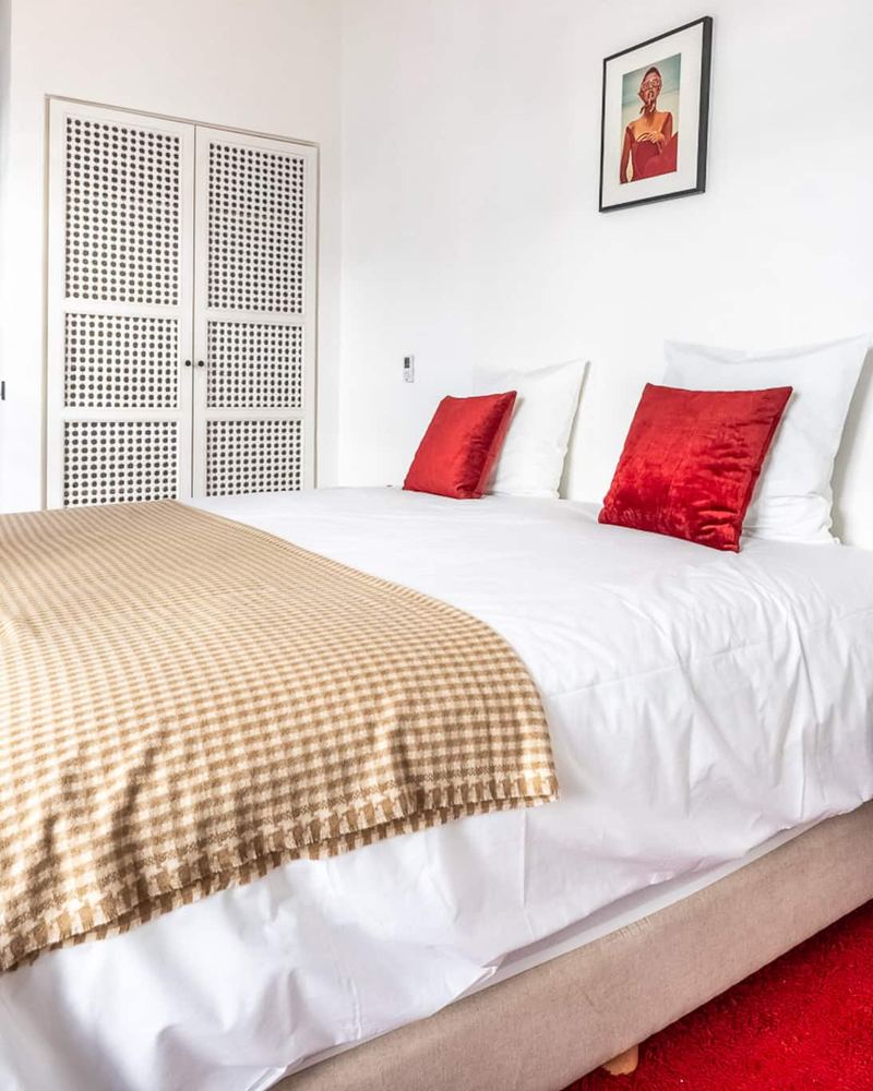 La chambre 3 : le lit queen, ses coussins rouges et un tapis rouge.