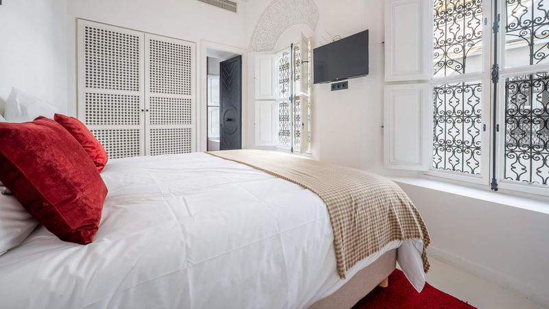 Bedroom 3 from the other side: the queen bed, a wardrobe with pierced doors and a wrought-iron window.