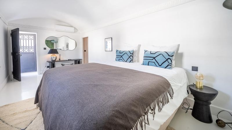Bedroom 4: the queen bed with patterned blue cushions, against a white wall.