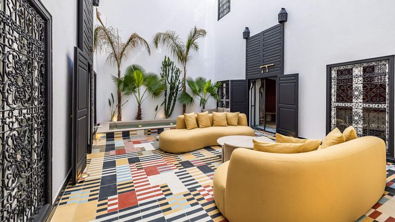 The two curved mustard sofas around a round low table, with the pool and the palms behind.