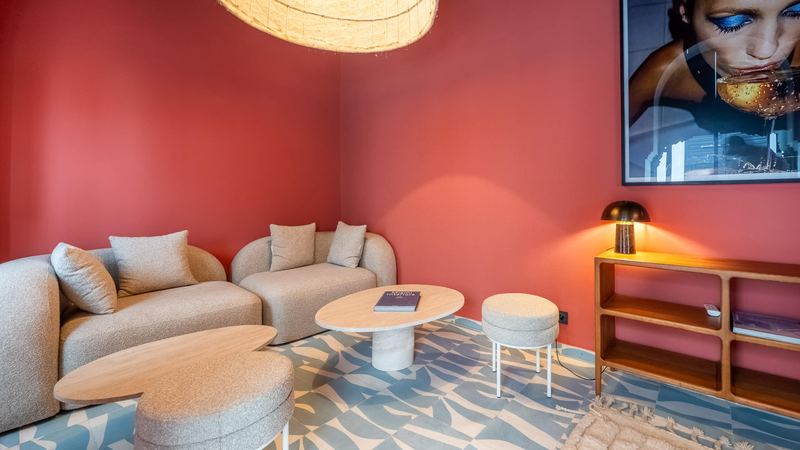 The sitting area with terracotta-pink walls: two pale, rounded sofas and low tables.