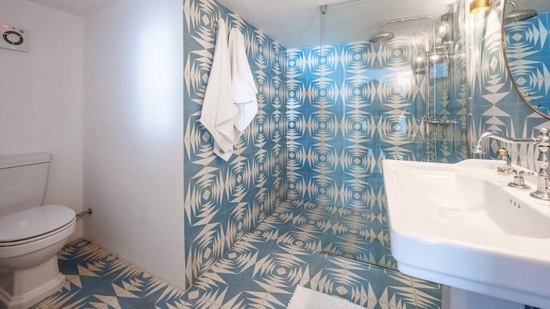 A bathroom with geometric blue tiles, a hanging towel and a basin.